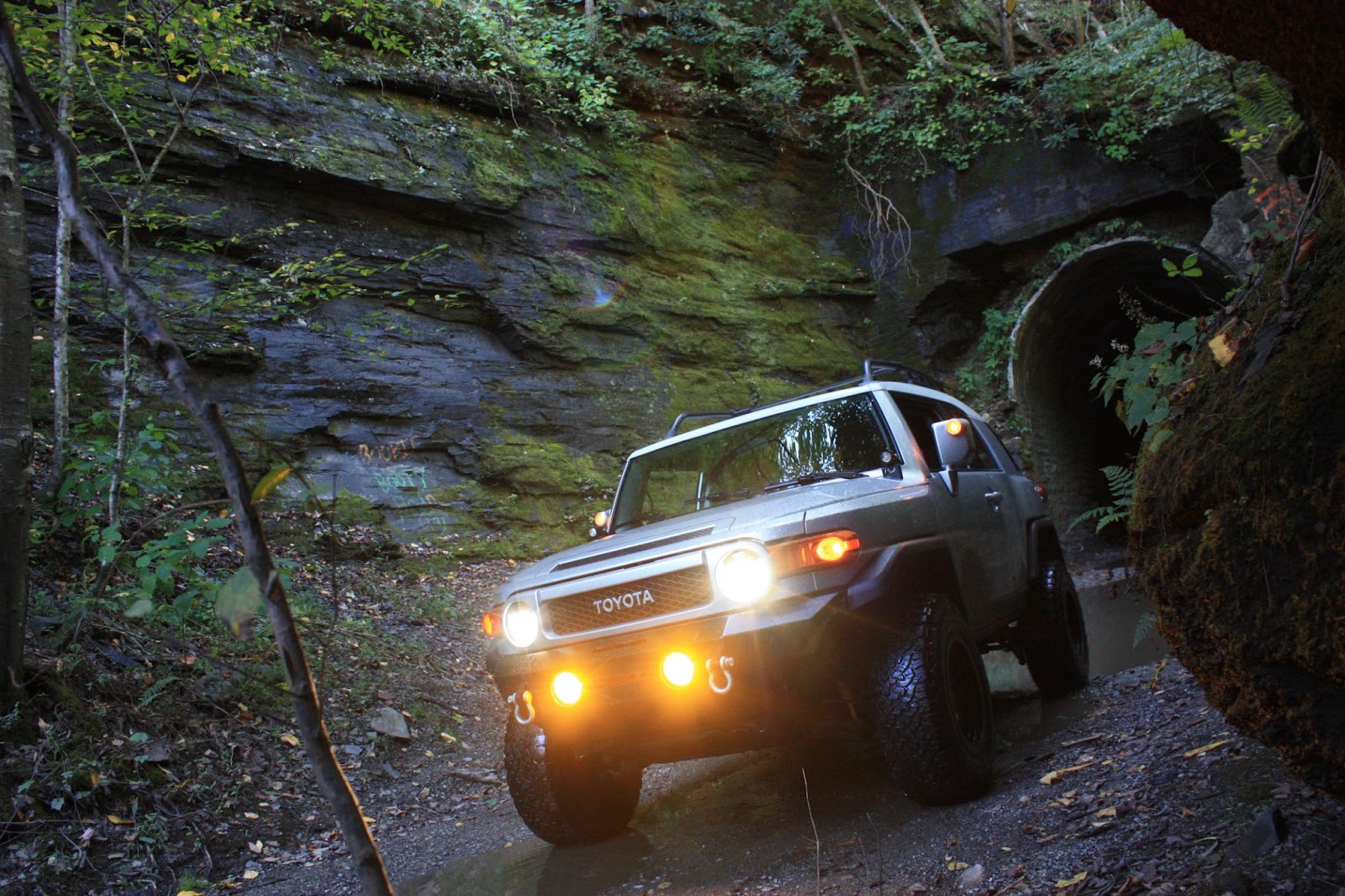 Toyota driving outside of tunnel with headlights on